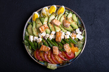 vegetable salad with chicken in a round plate on a black background