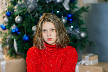 Happy emotional surprised young woman by Christmas tree in cozy living room, concept of happiness