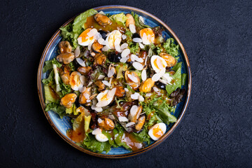 salad with mussels in a round plate on a black background
