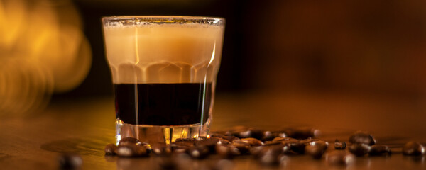 shot with coffee in the glass and coffee beans on wooden table in bar panorama