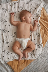 Little baby in diaper on white blanket, flat lay