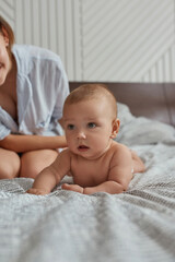Curious infant baby in bed looking away