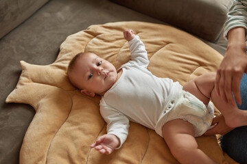 Sweet baby in white bodysuit during dressing