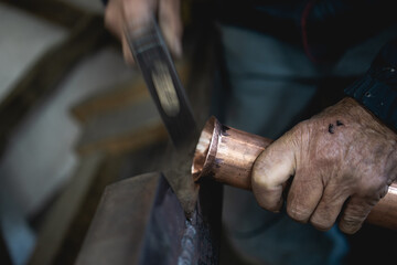 An old man,a worker in a workshop for making cauldrons for an alcohol distillation.