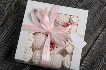 Homemade marshmallow in a gift box. Tied with a ribbon tied to a bow. On black pine boards.