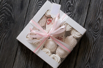 Homemade marshmallow in a gift box. Tied with a ribbon tied to a bow. On black pine boards.