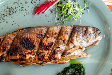 Baked trout with radishes and green spinach. View from above. Free space for your text. Lifestyle. Grilled trout