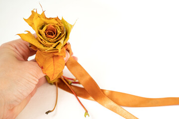 Finished rose flower assembled from maple leaves tied with a ribbon. How to make an autumn bouquet of roses from colorful maple leaves. DIY concept. Step 10 of 12 step-by-step photo instruction