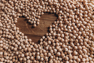 Heart on a background of chickpeas. Chickpeas on a wooden table