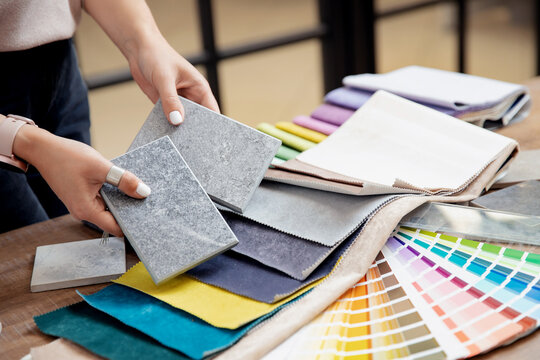 Hand of woman designer chooses ceramic tile and set fabrics for curtains in textile. Concept design interior