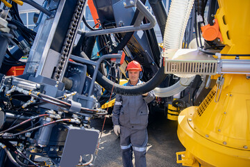 Engineer in hard hat and uniform is servicing hydraulic systems of mining equipment for descending...