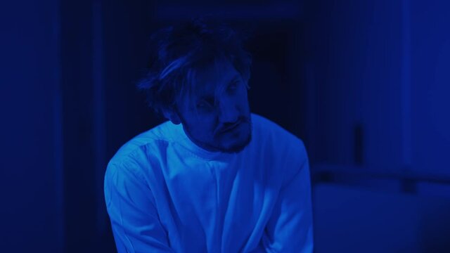 A mad male patient in straitjacket is going crazy in a mental hospital. Close up of mentally ill man with psychic disorders and bipolar disease. Concept of paranoia or schizophrenia and madness.