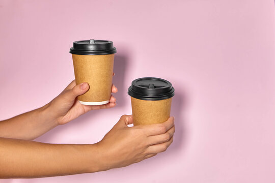 Close-up On A Pink Background, A Woman's Hand Holds A Paper Cup With Coffee In A Stand. Coffee Or Tea To Go. People Hands Passing One Another Cup Of Coffee, Coffee Delivery.