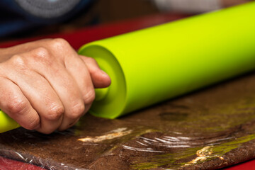 Hands of unrecognizable person rolling out the cocoa dough with a rolling pin for the preparation of the homemade Argentine alfajores recipe