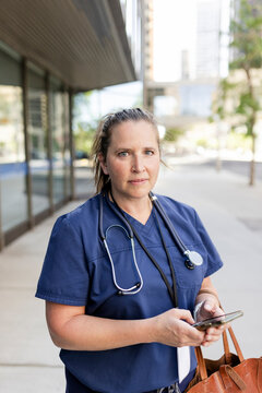 Portrait Of Nurse Holding Phone On Sidewalk