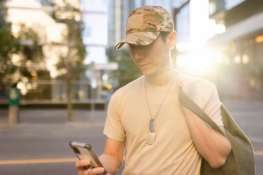 Soldier looking at phone in city center