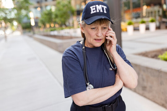 EMS Worker Talking On Phone On Sidewalk