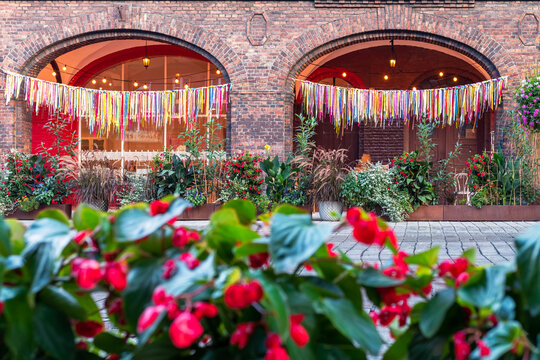 Detail of the arcade in an old, traditional, silesian brick block house in Nikiszowiec, Katowice, Poland. Colorful ribbons hanging as a decoration in arcade. Red flowers in the foreground.