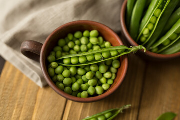 Сlay mug with fresh green peas on table