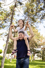 Grandfather holds his niece on his shoulders, he enjoys of a good day together in nature.