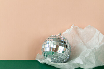 Disco ball in torn paper against emerald green and pale pink background