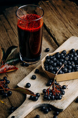 Fresh aronia berries and berry juice in a glass.