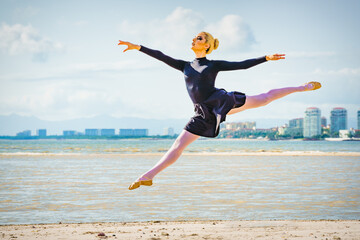 Ballet dancer doing ballet moves at the beach jumps and dance moves