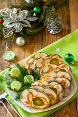 Festive snack. Baked mackerel roll stuffed with cheese, carrots, eggs and pickled cucumber, served on the Christmas table.