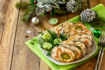 Festive snack. Baked mackerel roll stuffed with cheese, carrots, eggs and pickled cucumber, served on the Christmas table. Copy space.