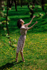 Young attractive woman with curly long hair posing in spring blooming garden, apple trees
