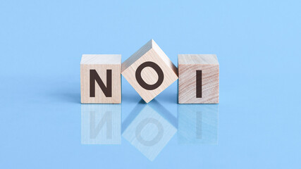 NOI word is made of wooden cubes lying on the blue table, concept