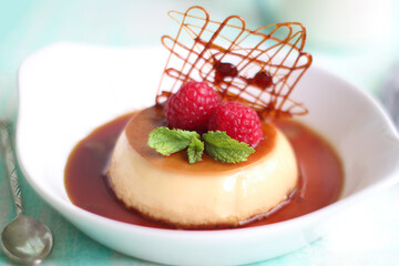 Selective focus of French caramel custard pudding in plate with spun sugar decoration, mint leaf...