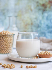A glass of homemade healthy soy milk with its bean in a white plate, alternative healthy nondairy milk and for diet concept  