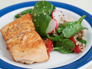 Healthy grilled salmon with quinoa salad, spinach, radish and cherry tomatoes. A healthy food concept for diet and eat clean with full nutrition benefits 