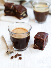 A cup of hot espresso coffee and beans with a piece of hazelnuts brownie on wooden table 