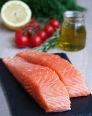 Fillet of fresh raw salmon with vegetables and ingredients with a bottle of olive oil, it's a common food fish classified as an oily fish with a rich content of protein and omega-3 fatty acids