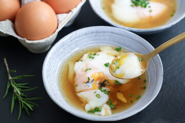 Selective focus of traditional Japanese hot spring egg (Onsen Tamago) in a bowl with spoon to eating, it's a method of boiling eggs in the hot springs of Japan. Taste like soft custard and smooth 