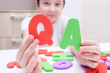 A boy holding colorful letters Q and A, questions and answers concept, solvation kids problems