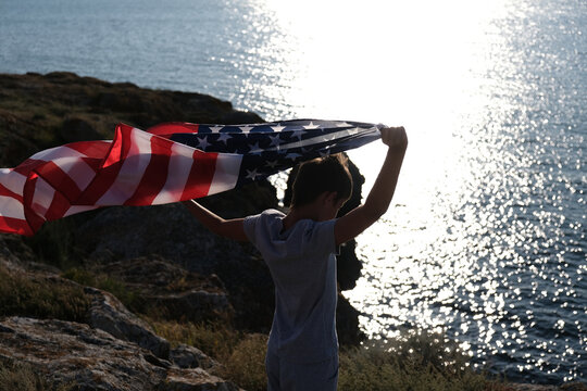 A boy holding waving US flag, beeng a patriot concept