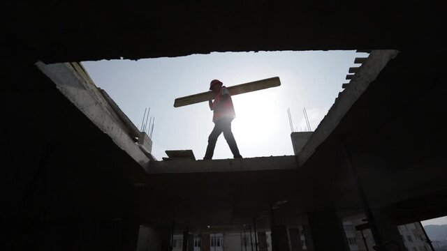 Construction works. working man carries a beam on his shoulders