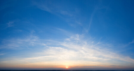 Naklejka na ściany i meble Dramatic sunset, the sun's rays shine through the clouds.