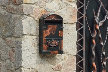 one colored metal mailbox hanging on a gray stone wall of a fence in the street