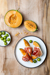 Fresh cantaloupe melon with jamon or prosciutto and green olives. Traditional Spanish and Italian appetizer, antipasti snack. Top view