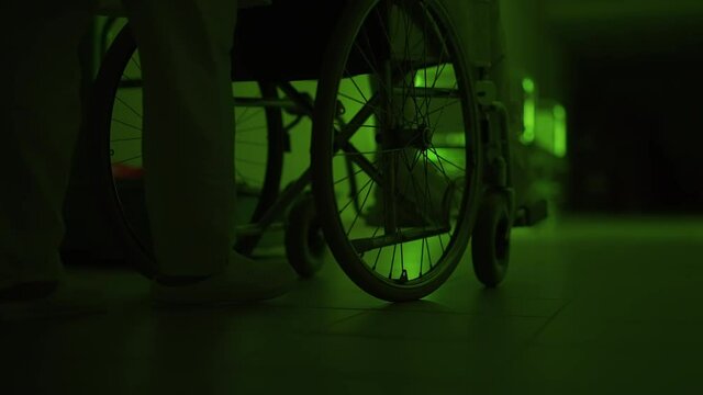 A paramedic is driving a mad male patient in wheelchair down corridor in mental hospital. Ill person in straitjacket is going crazy. Concept of paranoia or schizophrenia and madness. Wheels close up.