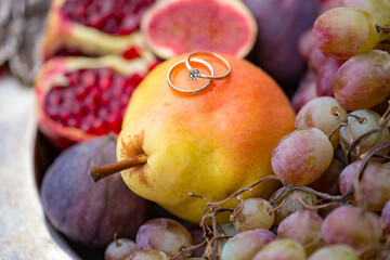 pear, pomegranate and grapes with wedding rings