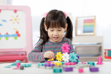 young girl plays creative gear blocks for home schooling