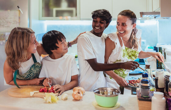 a multiracial family has fun cooking together at home. lesbian couple and multiracial family concept. Adoption.