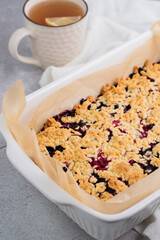 On a gray background, a blurred image of a baked shortbread cake with berries and a cup of tea.Homemade baking.
