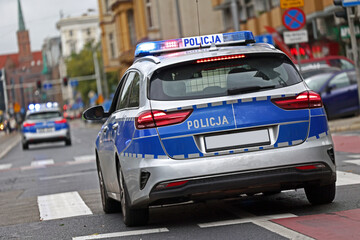 Samochód służbowy polskiej policji państwowej podczas akcji ratunkowej w mieście.  - obrazy, fototapety, plakaty