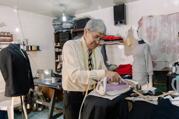 experienced mexican tailor ironing clothes